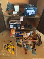 Wide view of shelving with various light bulbs, Kwikset deadbolt, packaging, light bulb changers, electronics, and other electrical components spread over 3 shelves.