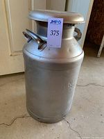 Front view of tall metal milk jug with sticker labeled '375'