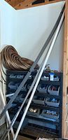 Photo showing assorted conduit pipes and coiled irrigation hose next to black shelving bins.