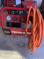 Red Porter Cable Jetstream air compressor with attached long orange air hose coiled on side. Shows model and 135 PSI specification.