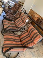 Four patio armchairs lined up, showing the metal frames and striped cushions