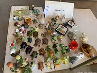 Overview of entire turtle collection showing various ceramic and porcelain turtle figurines, ashtrays and novelty items arranged on a flat surface.