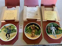 Three Wizard of Oz character plates - Scarecrow, Cowardly Lion, Tin Man - with certificates of authenticity and presentation boxes.