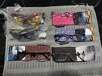 Photo showing six pairs of Foster Grant eyewear with cases, highlighting variety in frame and lens colors and patterns.