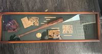 Photo of a wooden framed baseball shadow box containing a wooden bat, baseball, glove, photographs, player cards, newspaper clippings and a wireframe illustration of a catcher's mask on a green felt background.