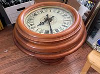 Top view of the oak clock table displaying the large clock face with Roman numerals under the glass dome.