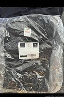 Black T-shirt sealed in plastic with Fruit of the Loom HeatGear label visible.