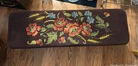 Top view showing floral needlepoint upholstery in vibrant colors on the bench seat.