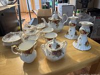 Grouped view of teapot, cups, saucers, creamer, sugar bowl, and candle holders