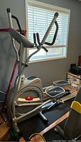 Side view of Schwinn 450 elliptical showing dual handlebars, foot pedals, and machine frame.
