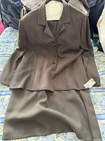 Brown women's dress and jacket with new tags on a bed.
