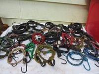 Top view of multiple bungee cords spread out on a surface showing a variety of colors, sizes, and hook types.