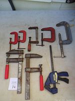 Photo showing eight clamps in various sizes laid out on table with paper numbered 74 included.