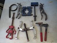 Entire set of eight gear pullers and related metal clamps/tools arranged on a flat surface, showing various sizes and shapes.