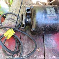 Side view of black heavy duty Hoover motor with attached power cord laying on wooden surface.