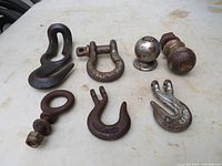 Seven assorted metal hooks and hardware pieces, showing surface rust and some wear.