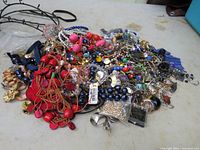 Wide view of assorted jewelry lot spread out showing various necklaces, bracelets, beads, and earrings.