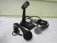 Three microphones: black AM 22 mic, black Rock Band style mic, and TOA paging microphone on stand with cables