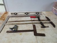 Photo of two metal clamps and three rusty angle tools with aluminum level on table