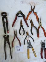 Full view of 11 assorted hand tools laid out on white background showing variety and condition with visible surface rust and colored handles.
