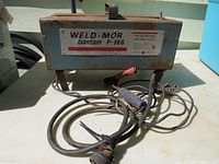 Front view of the welding machine with attached cable and torch showing Weld-Mor Bantam F-166 model label.