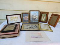 Lot of vintage picture frames displayed on surface with several frames showing artwork, some stacked with additional glass and mattes visible