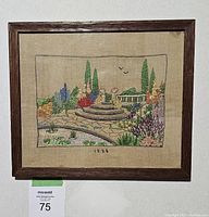Full view of antique framed crewel embroidery wall art hanging on wall, shows entire composition and frame.