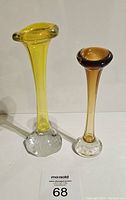 Two Aseda art glass vases with controlled bubble bases, yellow and brown, shown from the front on a white background.