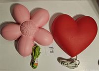 Top view of pink daisy lamp and red heart lamp with cords laid out, showing shape and color.