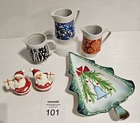 Photo showing all items in the lot including three mini pitchers, Santa salt and pepper shakers, and Christmas tree platter arranged together