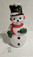 Front view of the modern retro snowman blow mold with black hat, red scarf, green mittens and buttons