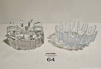 Two clear glass ashtrays shown side by side on a white surface, frontal view highlighting the vertical pin-like protrusions and clear solid glass construction.