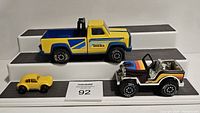 Three vintage Tonka cars displayed on black textured platforms.