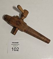 Top side view of vintage German wooden spigot showing the handle and precise wood grain texture with auction tag visible.
