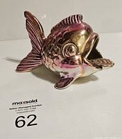 Front angle photo of vintage goldfish ashtray with metallic pinkish finish showcasing details in fins and scales.