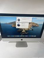 Front view of Apple iMac 21.5-inch showing desktop screen with macOS Catalina and software update window open.