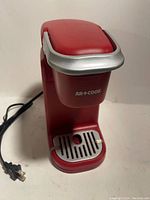Front angled view of red AR+Cook coffee maker showing power cord and drip tray