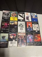 Photo showing 15 classic rock cassette tapes with album art visible on each case. Tape titles include Led Zeppelin I & II, The Cars, Peter & Gordon, Daryl Hall & John Oates, among others.
