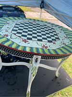 Full view of the hand-painted round table with chessboard on top, showing decorative floral and striped details.
