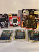 Photo shows all 6 games: one Sudoku handheld game, Star Wars plug and play TV game in package, and four Pachka handheld electronic games in original packaging.