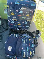 Photo showing both the kids rolling suitcase and the matching backpack with colorful vehicle illustrations on blue fabric.