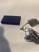 Closed blue Nintendo DS console with charger cable visible