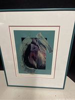 Framed abstract art print showing brushstroke-style textures with purple and black colors on teal background.