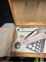 Image of artist palette with brushes, paint tube, stencils and small metal container lid