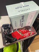 Box containing a red and white knit pet sweater and two harnesses with a Katziela Mesh Sling box
