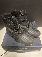 Front-side angled view of Tommy Hilfiger black snow boots with laces, showing overall shape and condition.