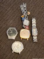 Photo of 5 fossil watches on a brown fabric surface, showing different styles including silver steel, gold-tone, charm bracelet style, with varied dial designs.