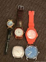 Five Fossil watches laid out showing diversity in styles, colors, and strap materials.