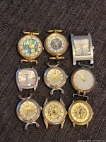 Nine Fossil wristwatches arranged in three rows on fabric background showing various dial styles and case shapes predominantly gold-tone metal.