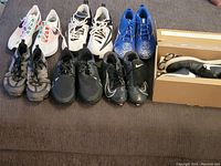 Seven pairs of Nike sneakers arranged on a surface showing various colors and designs from casual to cleats.